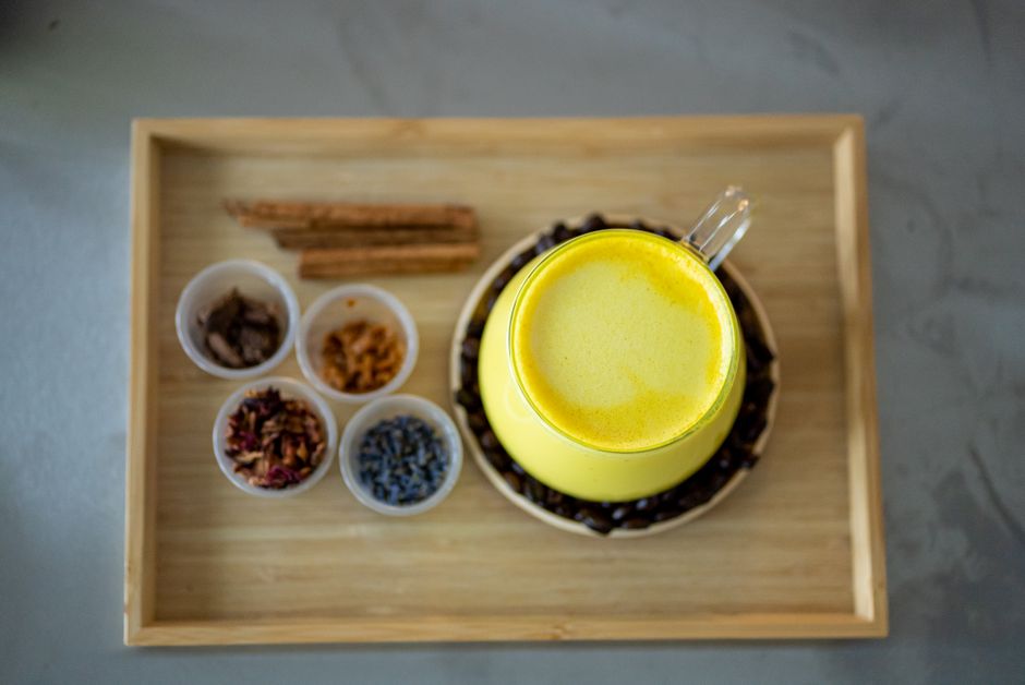 A top-down view of a turmeric latte surrounded by diverse spices for an aromatic experience.